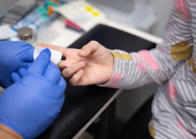Pediatric Services - child getting finger prick at doctor